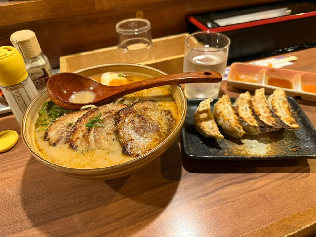 A bowl of ramen with gyoza on the side