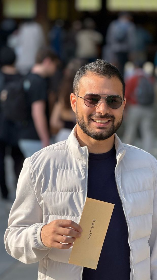Adir holding a written wish envelope at a shrine in Tokyo