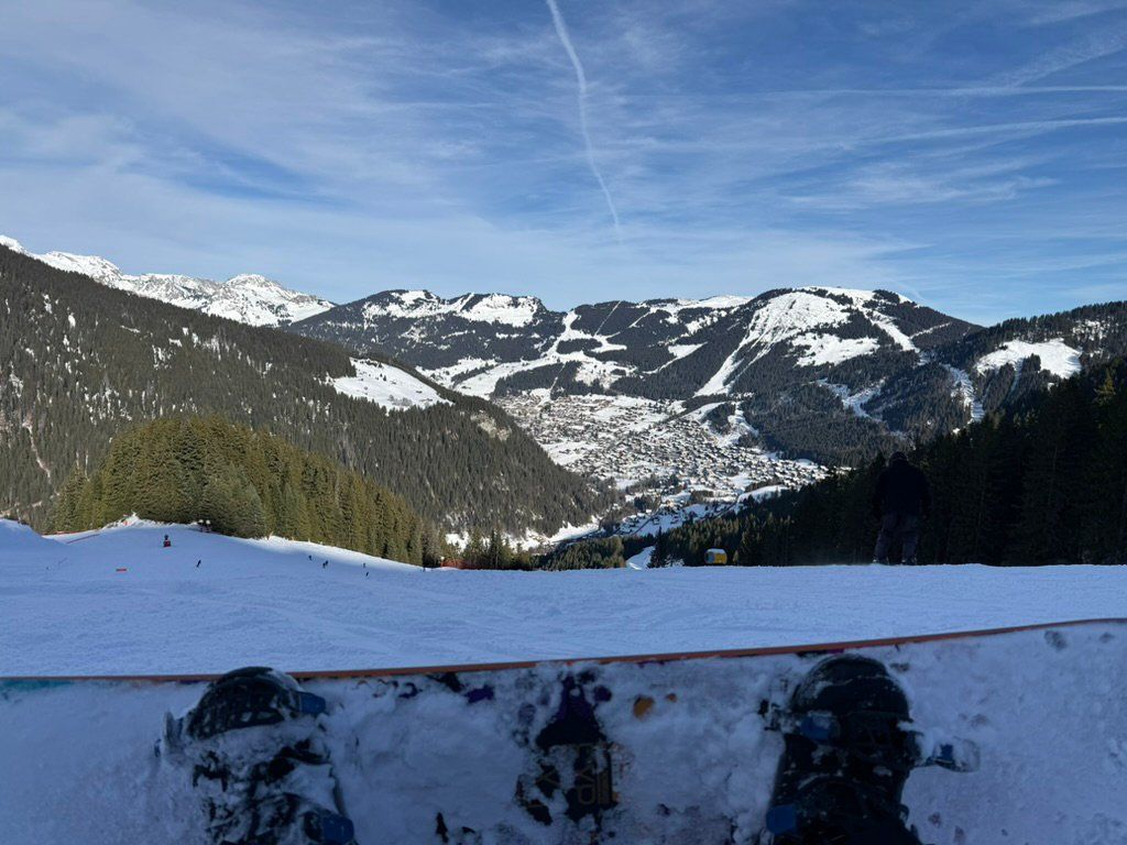 A snowboard resting above a snowy alpine valley and village