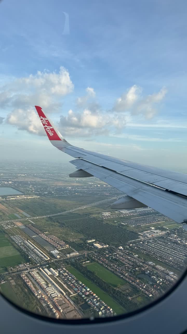 מבט על פאתי בנגקוק וכנף מטוס של AirAsia מחלון המטוס בזמן הגישה לנחיתה